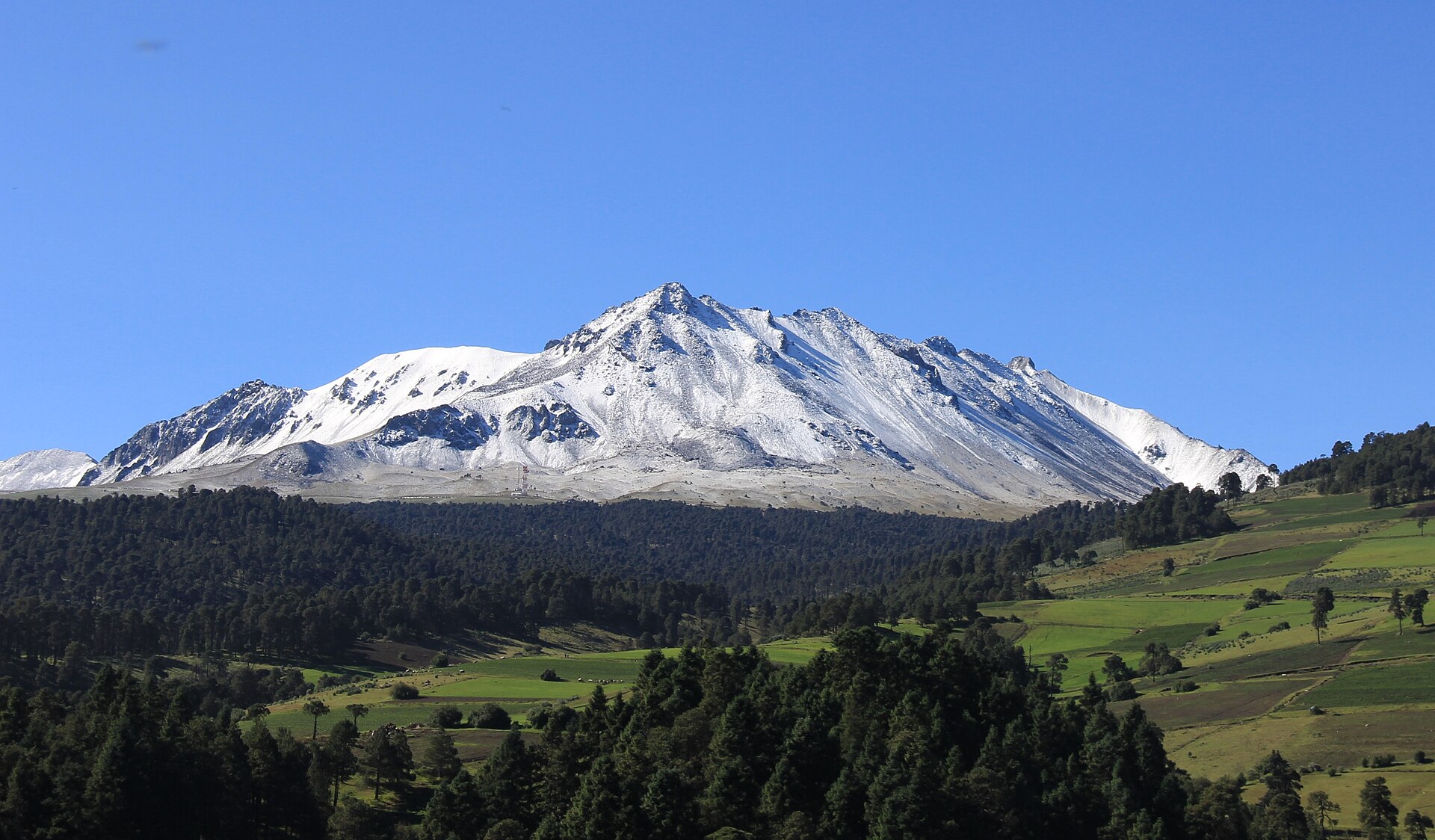 Snow-dusted Nevado de Toluca rising above forest and fields in the Toluca Valley